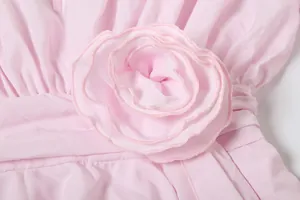 Dettaglio macro di un elegante fiore in tessuto rosa tridimensionale su un abito estivo