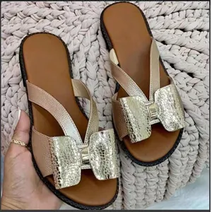 Elegant gold bow flat sandals for women featuring champagne metallic straps and comfort sole.
