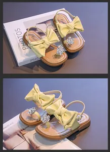 Detailed view of girls' yellow bow sandals with rhinestone flower accents
