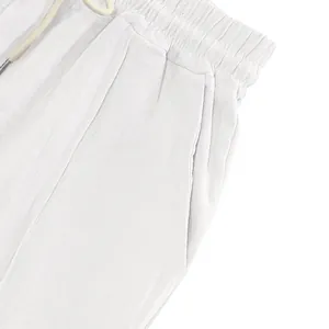 Close-up of white linen trousers featuring elastic waist with drawstring and side pocket.