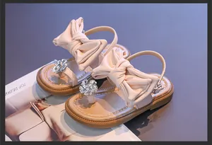 Detail view of pink girls sandals with oversized bow and sparkly rhinestone flower
