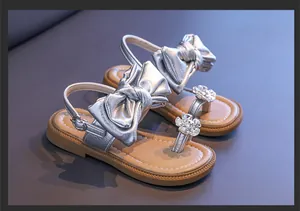 Side view of silver girls' sandals with large metallic bow and crystal flower