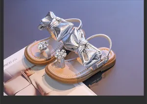 Detailed view of silver girls' sandals featuring large bows and sparkling rhinestone flowers.