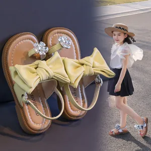 Elegant girl's summer sandals featuring a large yellow bow and sparkling rhinestone flowers