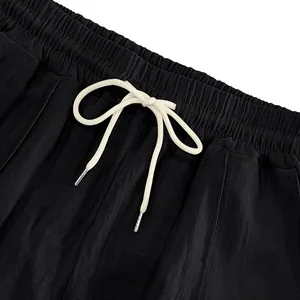 Close-up of black breathable linen pants with elastic waist and cream drawstring