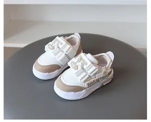 Nahaufnahme von weißen und khakifarbenen Kindersportschuhen mit weichen Sohlen