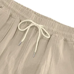 Detail of beige linen casual pants featuring elastic waistband and adjustable drawstring.