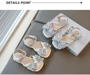 Détail des sandales blanches et argentées pour filles avec nœud en strass et bout carré.