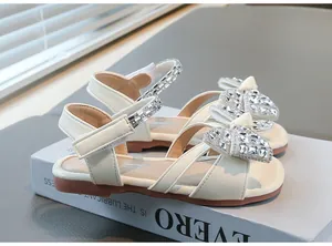 Détail de sandales crème pour fille avec nœud en strass et bout carré élégant.