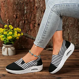 Casual black and white striped canvas wedge shoes for women on rustic wood background.