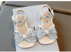 Vue détaillée des sandales blanches pour filles avec grand nœud en strass et bout carré.