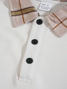 Detailed view of a white waffle knit polo shirt featuring a plaid collar and black buttons