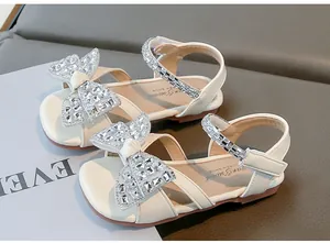 Gros plan sur les sandales de princesse blanches pour filles avec un nœud en strass brillant