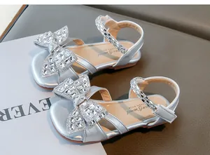 Détail des sandales argentées pour filles avec un grand nœud en strass brillants