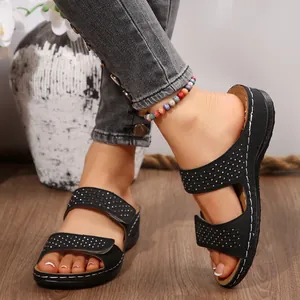 Vue détaillée de sandales compensées noires avec strass et brides velcro.