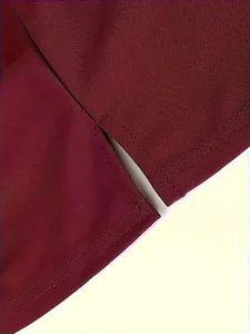Detaillierte Nahaufnahme des verstärkten Seitenschlitzes eines weinroten Poloshirts.