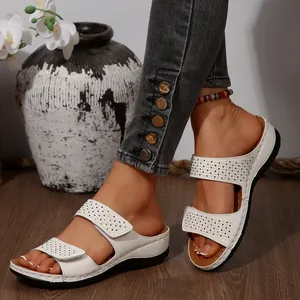 Gros plan de sandales compensées blanches avec brides en strass et velcro ajustable