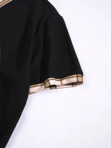 Close-up of black Polo shirt sleeve with classic beige plaid pattern cuff detail.
