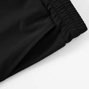 Close-up of black tactical shorts showing elastic waistband and side pocket detail.