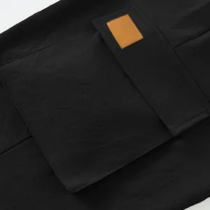 Close-up detail of a large cargo pocket with a tan patch on black tactical men's shorts