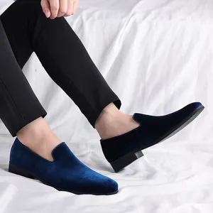 Vista detallada de mocasines de terciopelo azul marino para hombre con pantalón negro