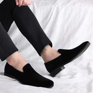 Detalle de mocasines de terciopelo negro usados por un modelo en tela blanca
