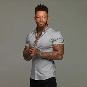 Close-up view of a light grey muscle fit short sleeve shirt on a tattooed male model.