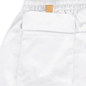 Detailed view of white tactical cargo shorts pocket and elastic waistband with leather tab
