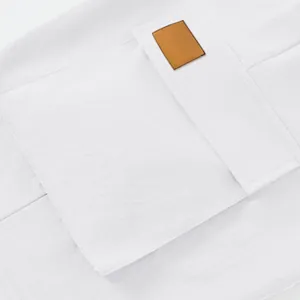 Close-up detail of white tactical cargo shorts featuring a large pocket and leather patch