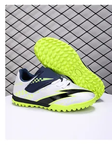 Macro view of junior turf soccer shoes with velcro straps and fluorescent green outsole