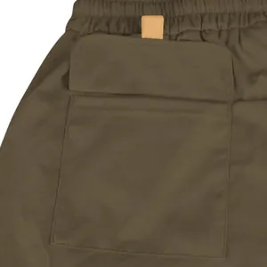 Macro detail view showing the durable flap pocket and tan tab of olive green tactical cargo shorts