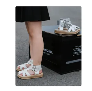 Detailansicht der weißen und silbernen gewebten geschlossenen Römersandalen für Mädchen.