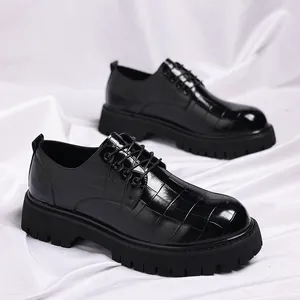 Dettaglio di scarpe da uomo in pelle nera con motivo a coccodrillo e suola spessa