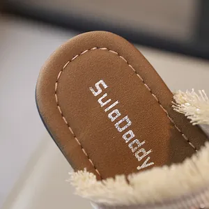 Detalle macro de la plantilla marrón de sandalias tejidas con flecos para mujer.
