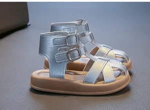 Nahaufnahme von silbernen geflochtenen Mädchen-Römersandalen mit Schnallenriemen