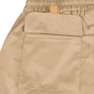 Detailed macro view showing the tactical cargo pocket and elastic waistband of mens khaki shorts