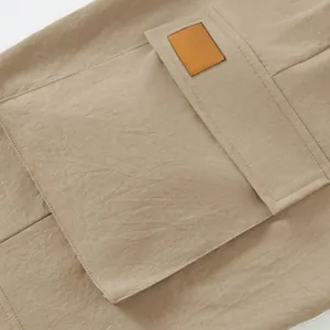 Detailed macro view showing the cargo pocket and leather patch on khaki cotton tactical shorts