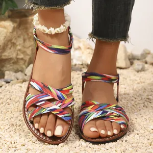 Detailansicht ethnischer flacher Sandalen mit bunten, gewebten Kreuzriemen auf Kies