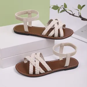 Detailansicht der beigefarbenen Flechtriemen und des elastischen Knöchelriemens an Sandalen.