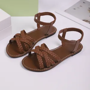 Detailansicht brauner geflochtener flacher Damensandalen mit gewebten Riemen und Textur.