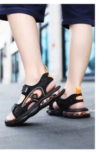 Vista lateral de sandalias deportivas negras para niños con detalles en naranja y suela de aire