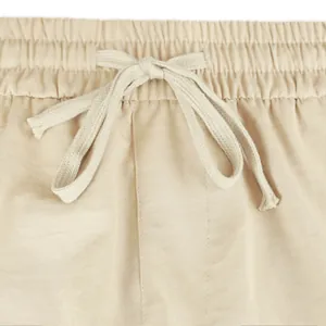 Detail view of the elastic waistband and adjustable drawstring on beige cargo shorts