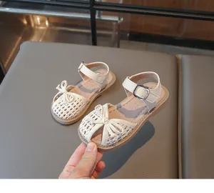 Close-up of cream braided children's sandals with bow detail and soft sole