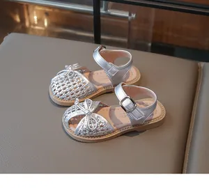Close-up of silver braided toddler girl sandals with bow and soft sole detail