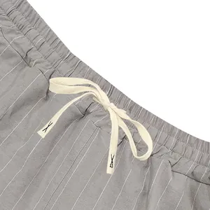 Detailed view of elastic waistband and cream drawstring on striped linen shorts