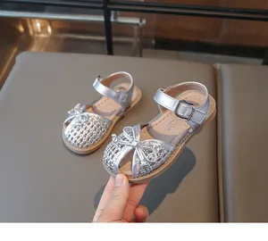 Close-up of silver woven girl sandals with breathable closed-toe design and bow detail