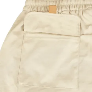 Macro detail shot showing the pocket flap and fabric texture of men's beige cargo shorts