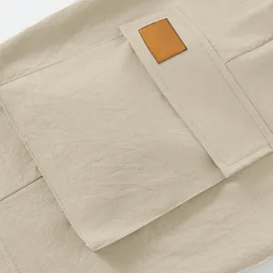 Close-up detail of a large cargo pocket with a leather patch on beige tactical shorts