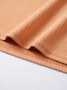 Primo piano del dettaglio in maglia a coste albicocca sull'orlo della maglietta da uomo