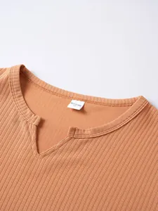 Dettaglio dello scollo a V a coste di una t-shirt arancione con etichetta taglia M